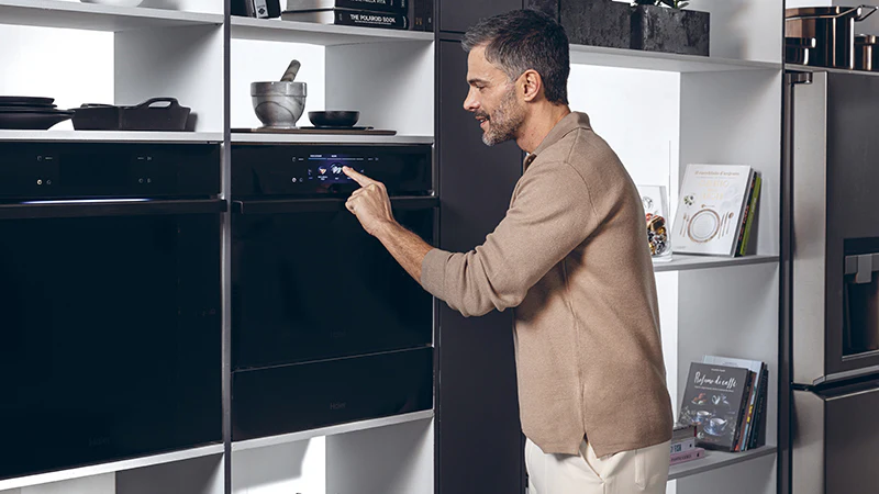 Persona che interagisce con un forno Haier da incasso in una cucina moderna