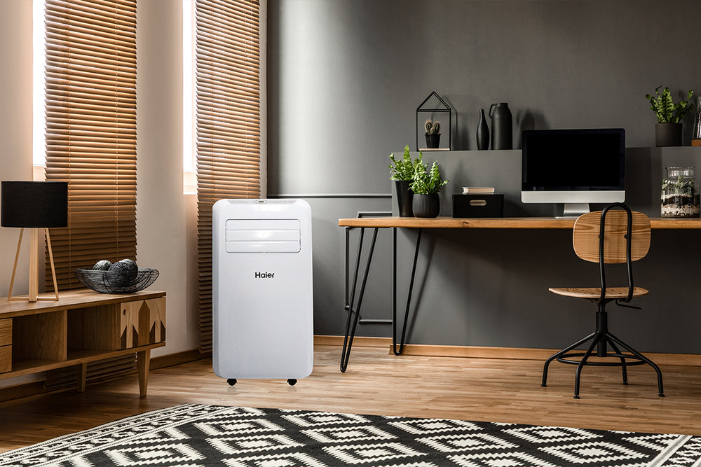 Condizionatore portatile Haier in uno studio domestico con scrivania, computer e piante decorative