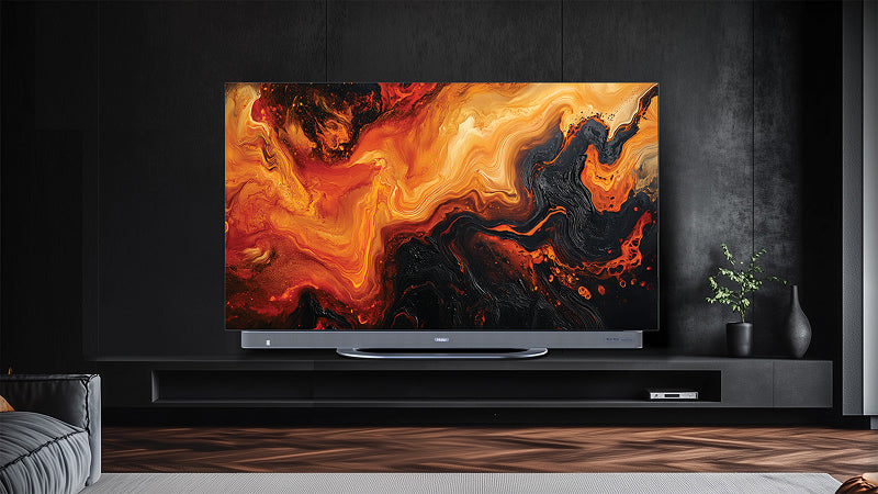 Televisore piatto di grandi dimensioni appoggiato su una parete scura, che mostra un'illustrazione astratta con colori caldi come rosso, arancione e nero. La stanza ha uno stile minimalista con un mobile nero sotto la TV, decorazioni di piante e un tappeto chiaro sul pavimento in legno scuro.