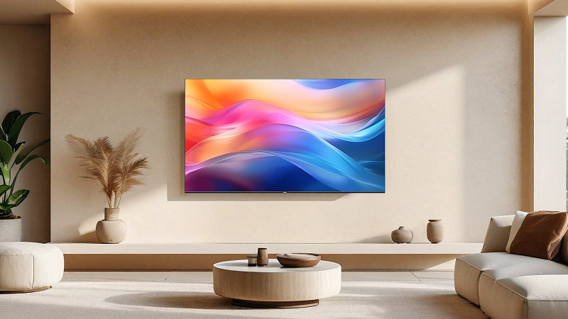 Interno di un soggiorno elegante e minimalista con pareti beige, decorato con un grande quadro astratto dai colori vivaci come rosa, blu, arancione e viola, appeso al centro. La stanza è arredata con un divano bianco con cuscini marroni, un tavolino rotondo di legno chiaro, e decorazioni di vasi e piante. La luce naturale illumina la stanza, creando un'atmosfera calda e accogliente.