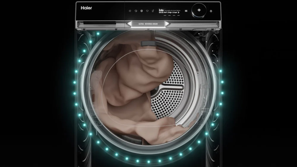 Lavatrice frontale moderna, con porta aperta che mostra il tamburo interno. La lavatrice è di colore nero con dettagli illuminati in blu e uno schermo digitale sulla parte superiore. All'interno del tamburo si vede un vestito chiaro, accanto a un piccolo pezzo di tessuto sospeso.