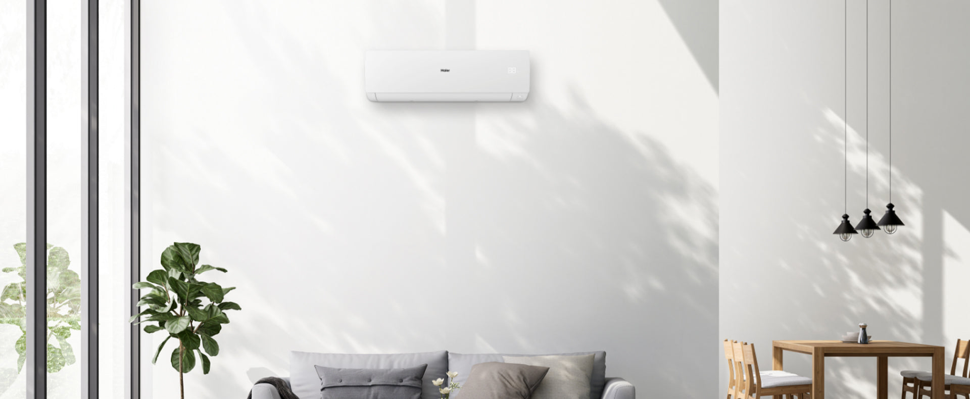 Condizionatore Sphera posto all'interno di un salotto. E' appeso al muro e sotto ha un divano con di fianco un tavolo da pranzo e delle lampade stile industriale.