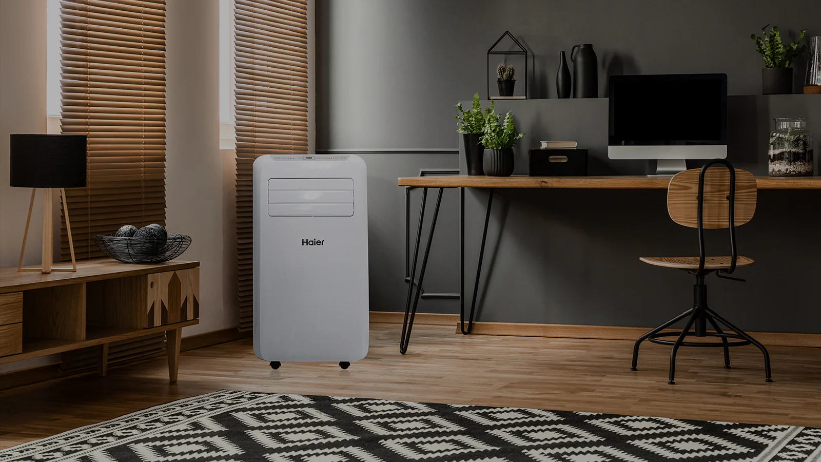 Condizionatore portatile posto in una stanza con una scrivania e un computer.