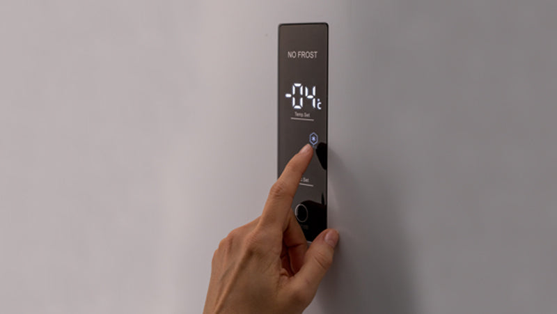 Focus su un dito maschile che preme il touch screen per selezionare la temperatura del frigorifero. 