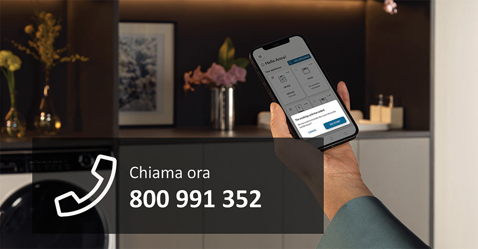 Mano maschile che tiene in mano il telefono con aperta l'app hon per attivare l'estensione di garanzia sul proprio elettrodomestico. 