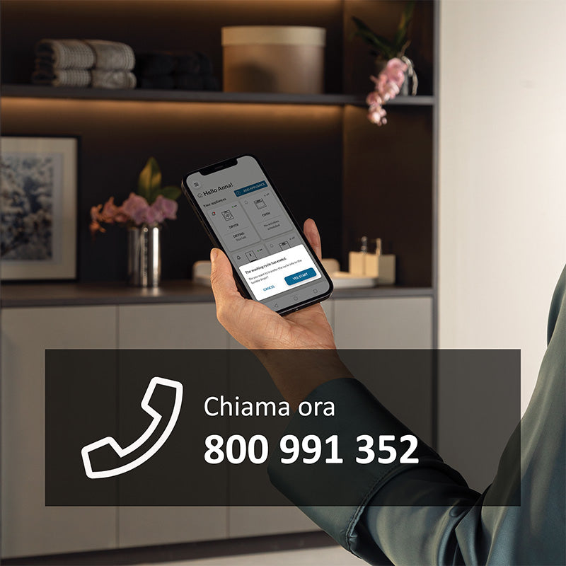 Mano maschile che tiene in mano il telefono con aperta l'app hon per attivare l'estensione di garanzia sul proprio elettrodomestico. 