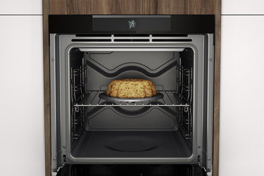 Interno di un forno da incasso con telecamera integrata, mentre cuoce una torta su una griglia centrale.