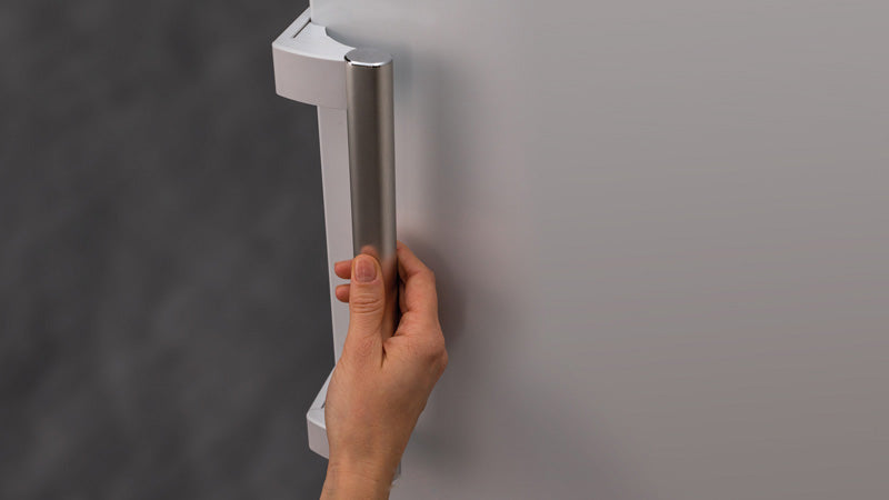 Focus su una mano che apre il freezer attraverso la maniglia robusta