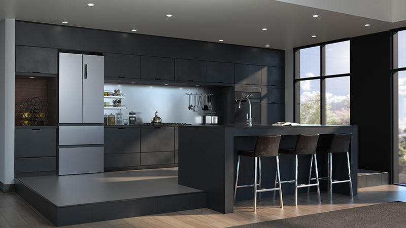 Cucina con focus su frigorifero inox french door. Vicino al frigorifero è presente un piano cottura a gas con un bollitore. Di fronte al frigorifero c'è una penisola.