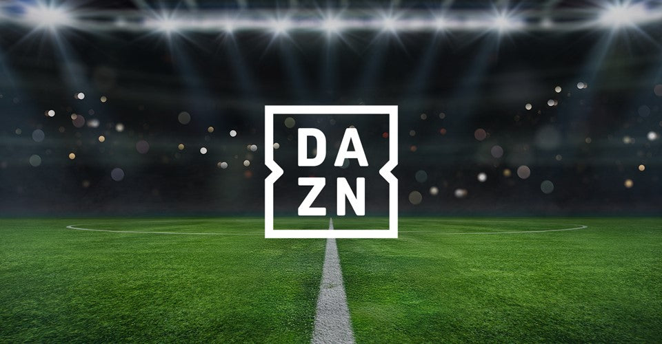 Immagine di un campo da calcio notturno con luci abbaglianti sopra e un logo centrale di DAZN che sovrasta il campo.