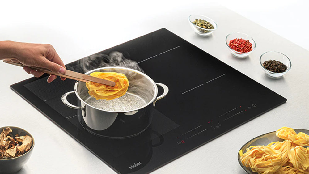 Piano cottura a induzione Haier Serie 4 con una pentola sui fornelli per preparare la pasta